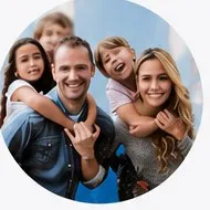 A family of five laughing together outdoors.