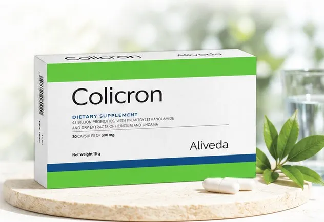 A carton of Colicron dietary supplement by Aliveda on a stone plinth beside a single capsule.