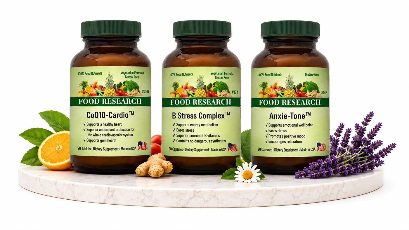 Three Food Research bottles — CoQ10-Cardio, B Stress Complex and Anxie-Tone — on a marble plinth with orange, ginger, chamomile and lavender.